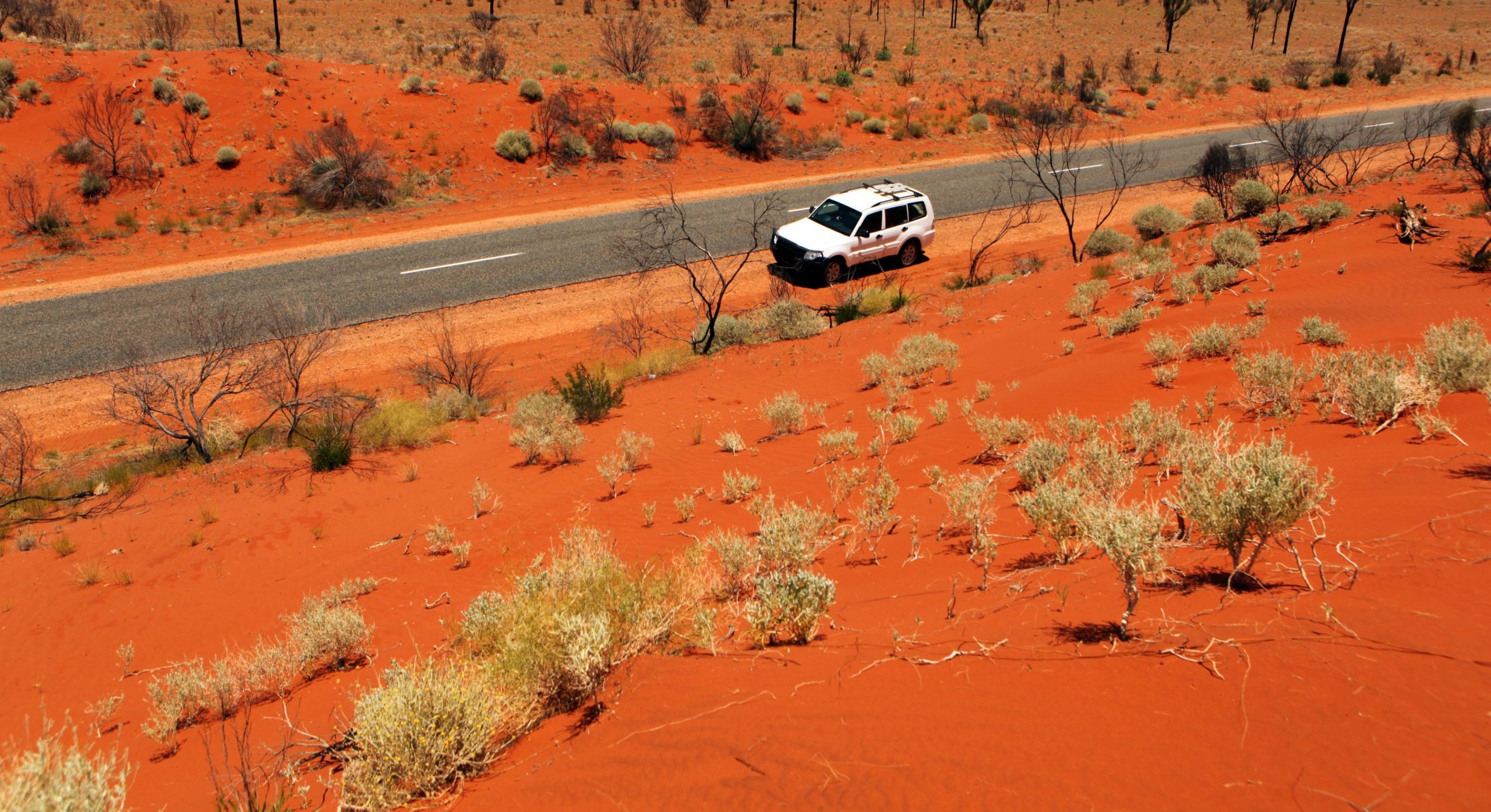 Car Driving on The Road Red Through Australian Outback Landscape